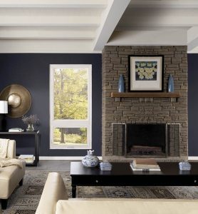 Rectangular picture window next to brick fireplace in an upscale, rustic living room