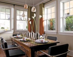 Dining room with table set for a dinner party surrounded by four beautiful double-hung windows