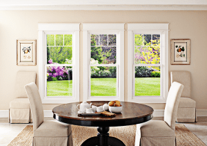 Table for two with chairs in front of three double-hung windows side by side in a home with beige and brown decor